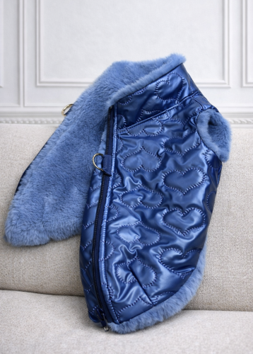 Pikowana kurtka dla psa w kolorze niebieskim, z miękkim futerkiem przy kołnierzu, prezentowana na manekinie psa na jasnym tle. Quilted luxury dog jacket in blue with a soft faux fur collar, displayed on a dog mannequin against a light background.