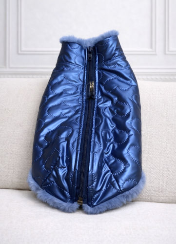 Pikowana kurtka dla psa w kolorze niebieskim, z miękkim futerkiem przy kołnierzu, prezentowana na manekinie psa na jasnym tle. Quilted luxury dog jacket in blue with a soft faux fur collar, displayed on a dog mannequin against a light background.